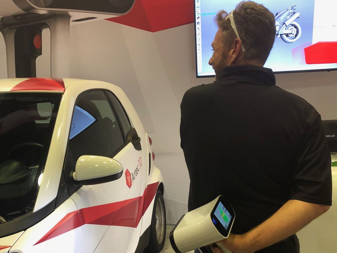 Scanning a car with an Artec Leo held one-handed, the mesh building on the screen behind